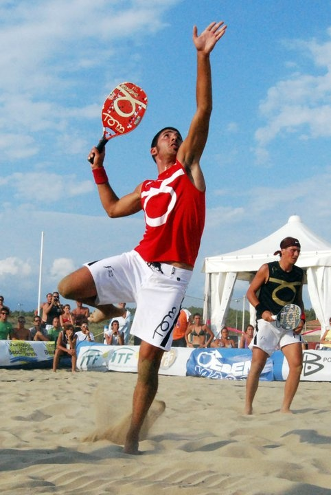 Atleta sacando em uma partida de beach tennis na areia